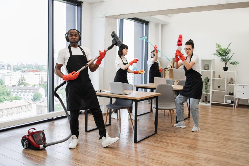 Team of janitors performing routine cleaning tasks in a modern office, using vacuum cleaners and mops while keeping the workspace organized