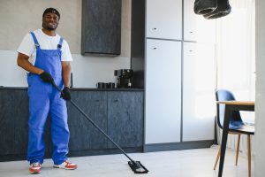 Professional cleaner mopping the floor in a commercial kitchen area as part of regular janitorial maintenance
